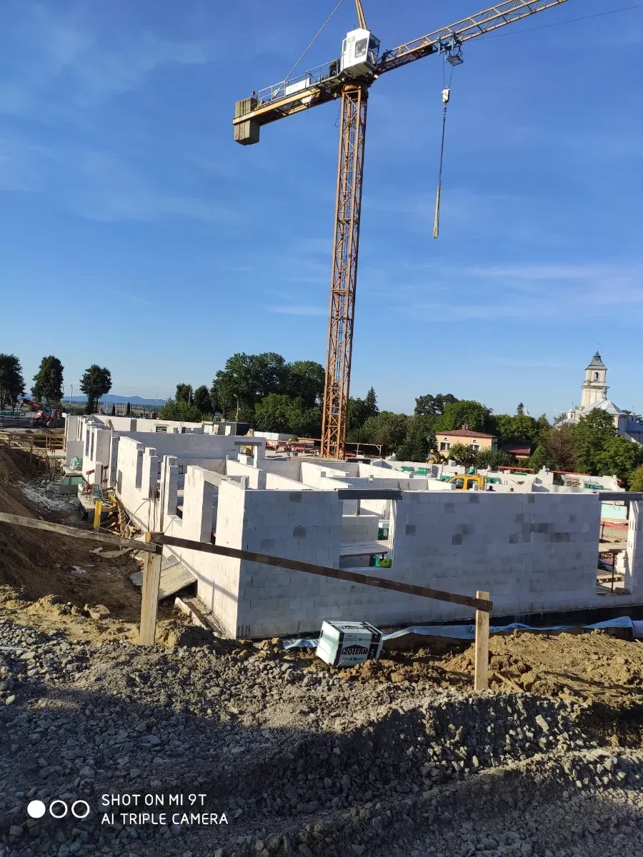 Fundamenty i ściany w trakcie budowy, dźwig na placu